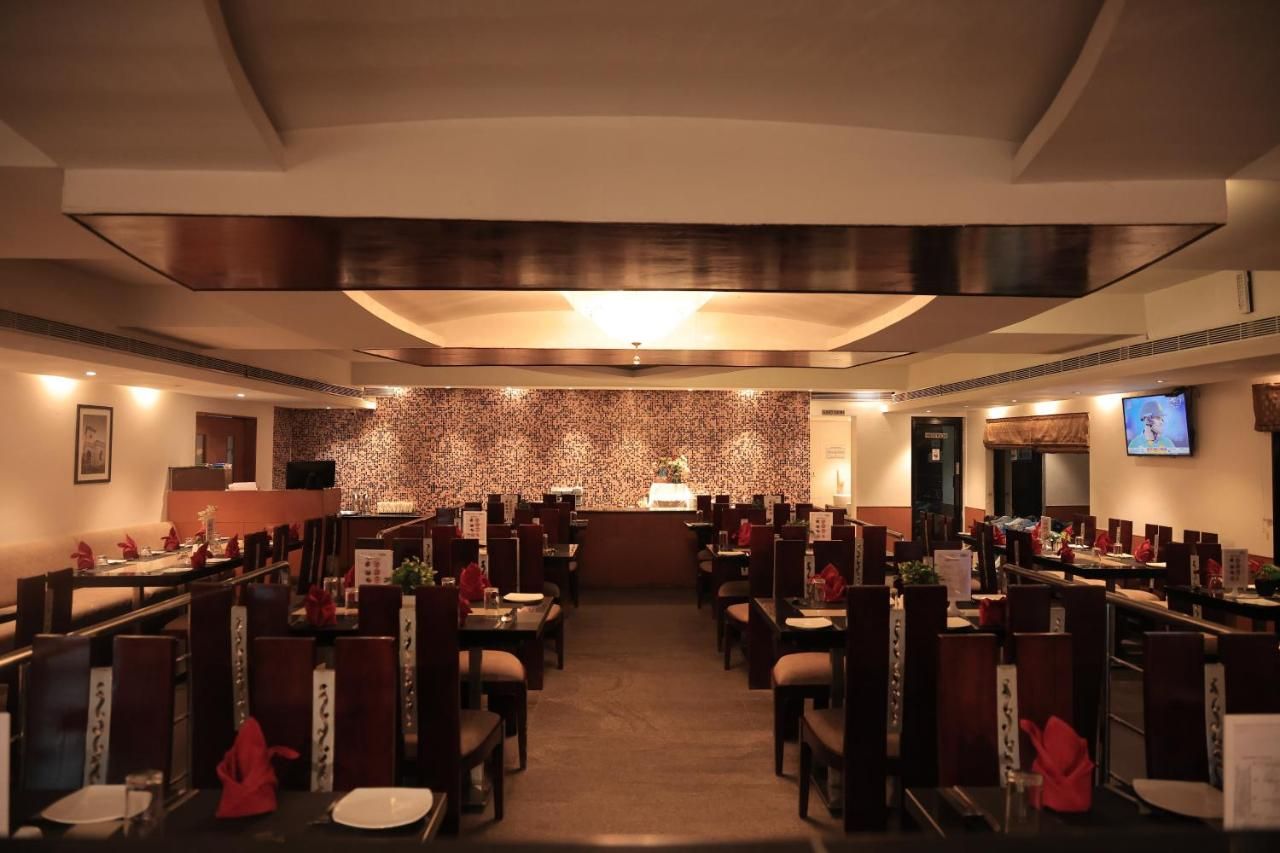 A restaurant with a patterned wall, multiple dining tables, and chairs.