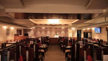 A restaurant with a patterned wall, multiple dining tables, and chairs.