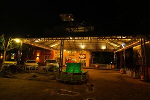 A nighttime view of a building with a covered entrance, a green-lit fountain, and a sign for 'MGM.' - Mgm Vailankanni Residency (Pattukkottai)
