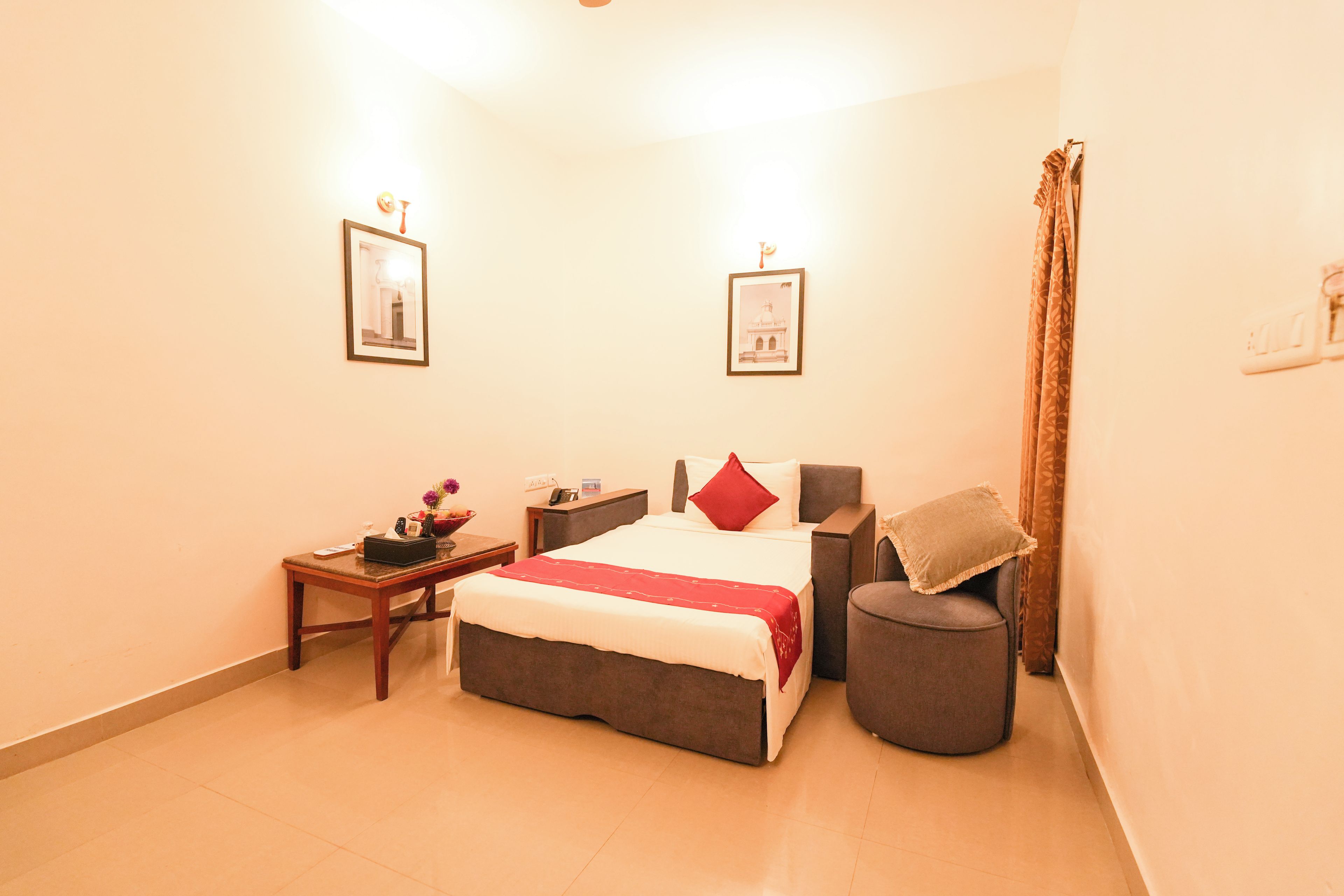 A bedroom with a bed, bedside tables, a nightstand, a chair, and a curtain.