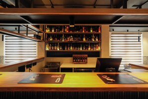 A bar area with shelves of liquor bottles, a laptop on a table, and a menu on the counter. - Mgm Vailankanni Residency (Pattukkottai)