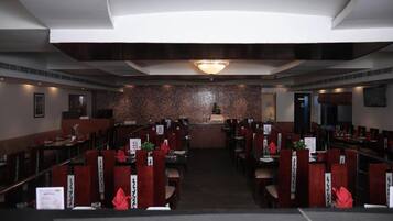 A restaurant with a central counter, multiple dining tables, and booths.