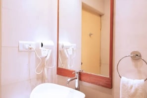 Une salle de bain équipée d’un lavabo, d’un miroir, d’un porte-serviettes et d’un sèche-cheveux.