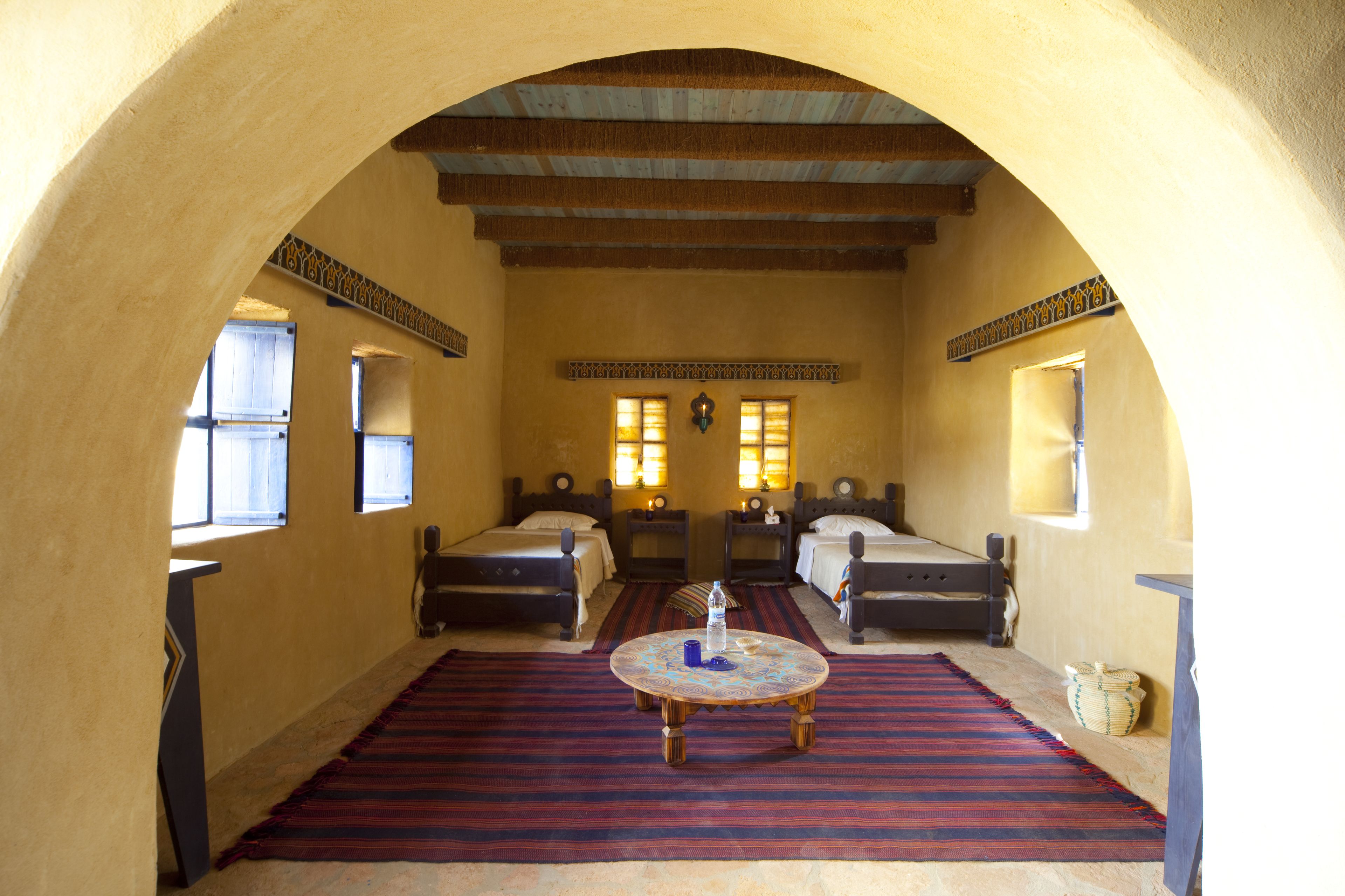 Une chambre avec deux lits, une table ronde et un tapis à motifs.