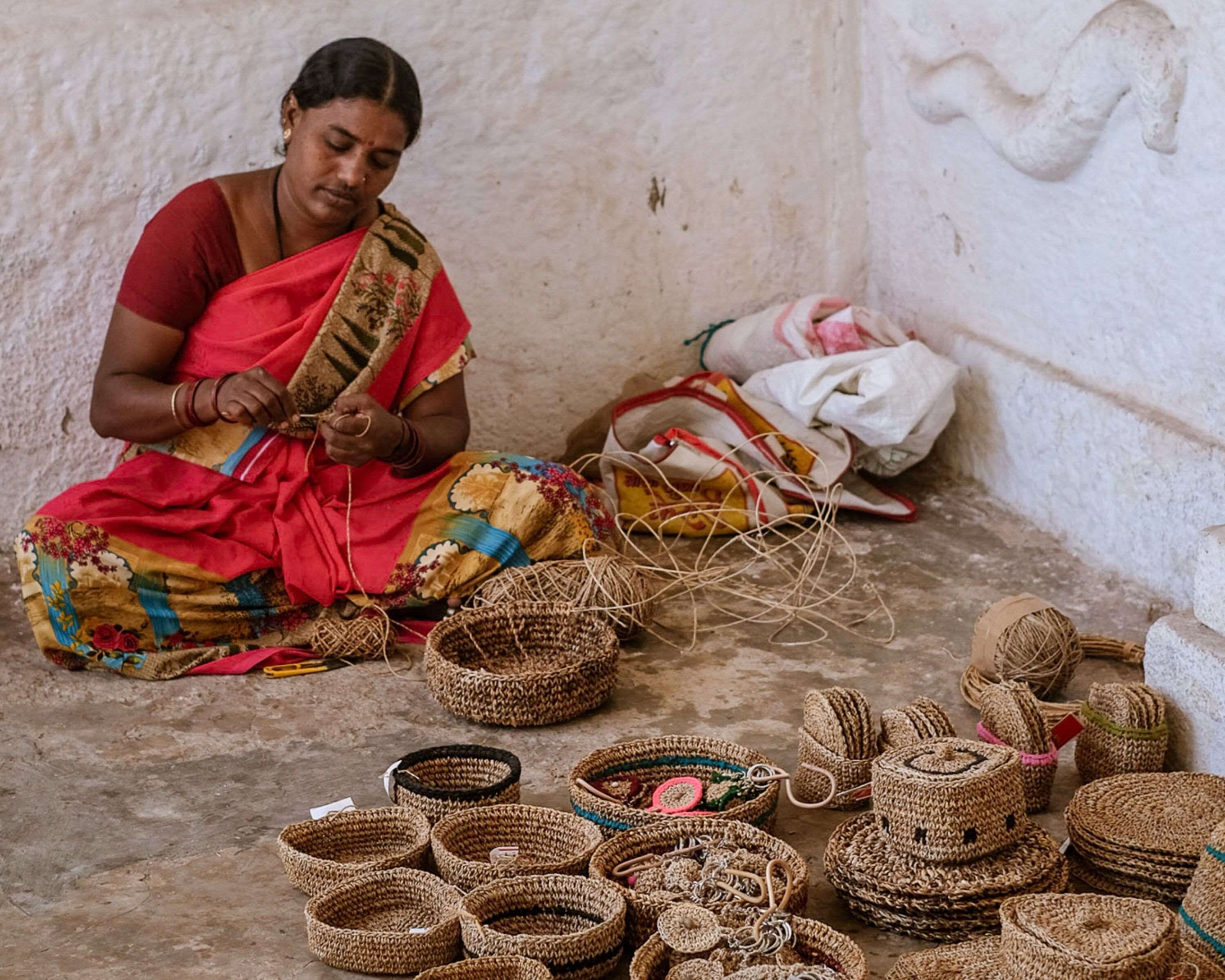 A person sitting on the floor, weaving baskets.
