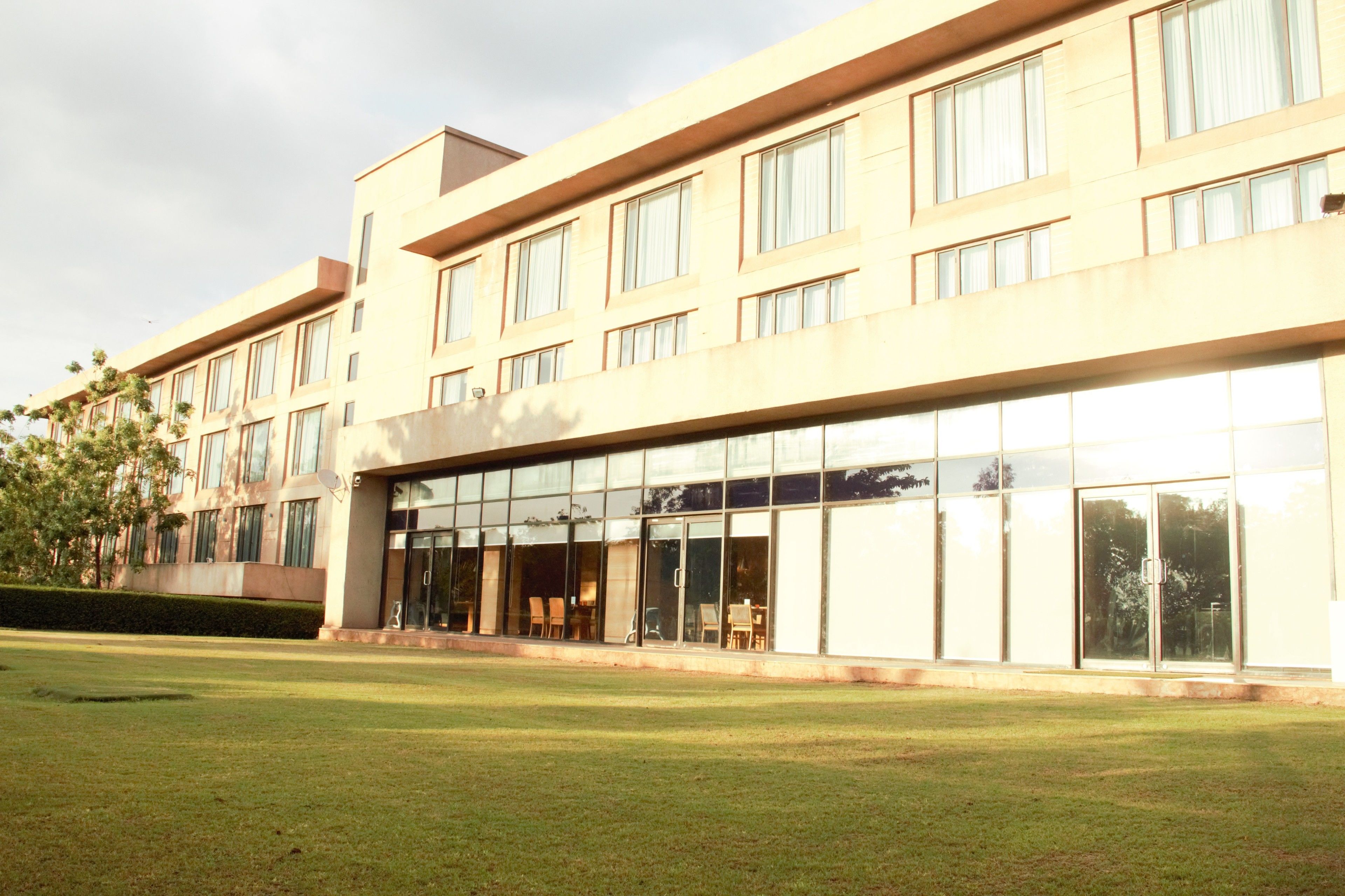 A modern hotel with a flat facade, large windows, and a well-maintained lawn.