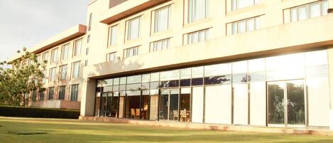 A modern hotel with a flat facade, large windows, and a well-maintained lawn.