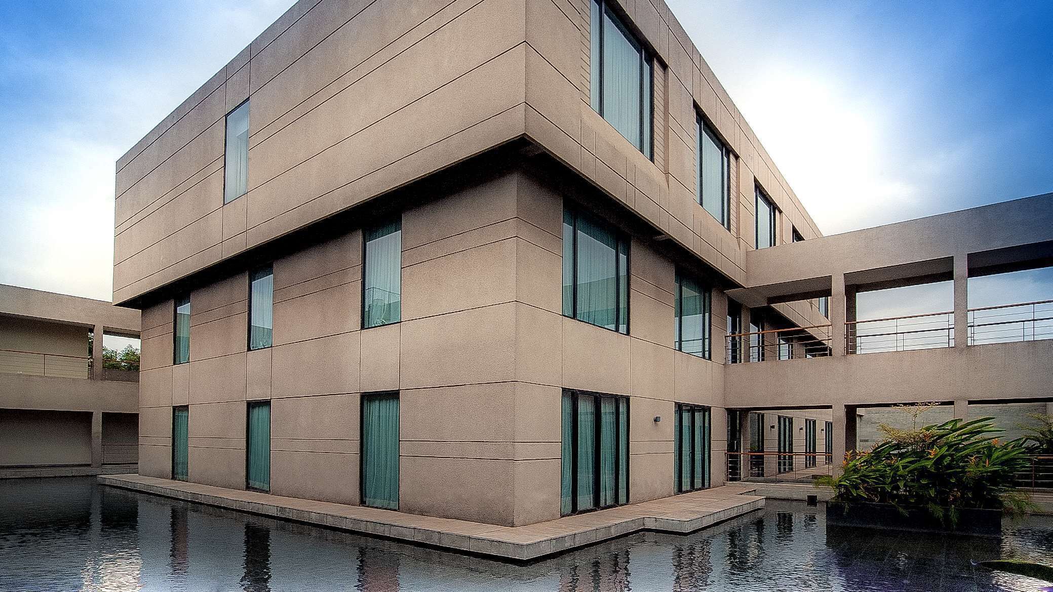 A modern building with a flat roof, multiple windows, and a water feature in front.