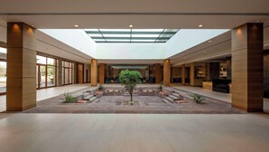 Un hall d’entrée spacieux avec un espace salon central, une verrière et un comptoir d’accueil.