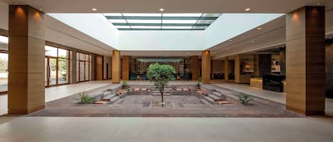 A spacious lobby with a central seating area, a skylight, and a reception desk.