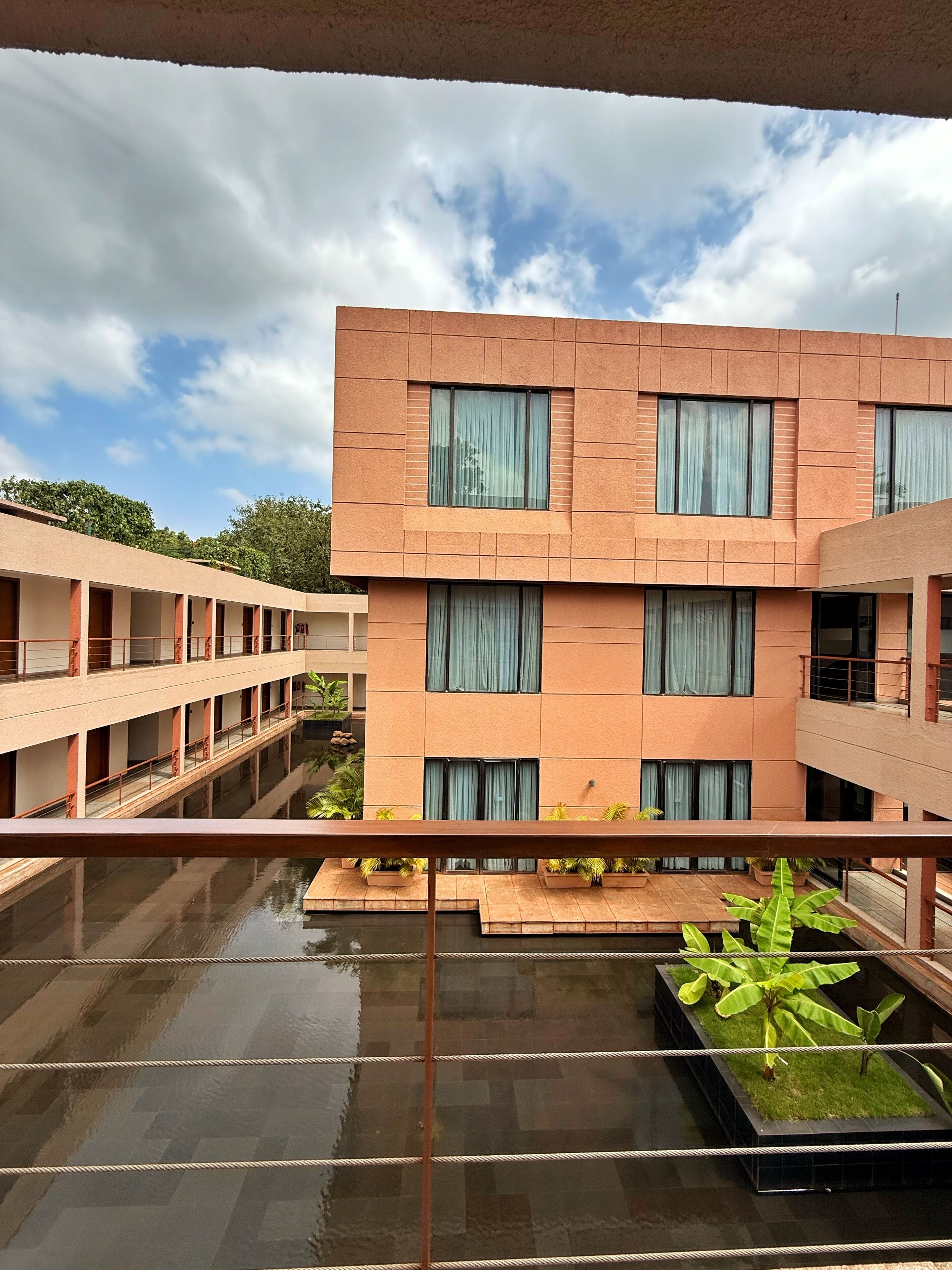 Un edificio moderno de varios pisos, con grandes ventanales y un patio con fuentes y plantas.
