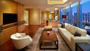 Een moderne hotelkamer met een groot raam met uitzicht op de stad, een flatscreen televisie aan de muur, een bank, een bijzettafeltje en een zithoek met een comfortabele bank.