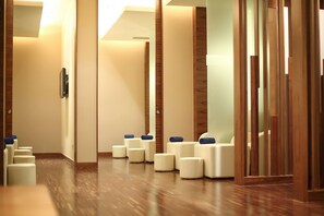 A hotel lobby with a wooden floor, a reception desk, and several seating areas with cushions.