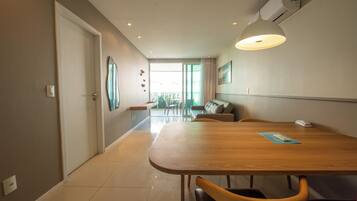 A modern dining area with a wooden table, chairs, a sofa, and a large window with a view.