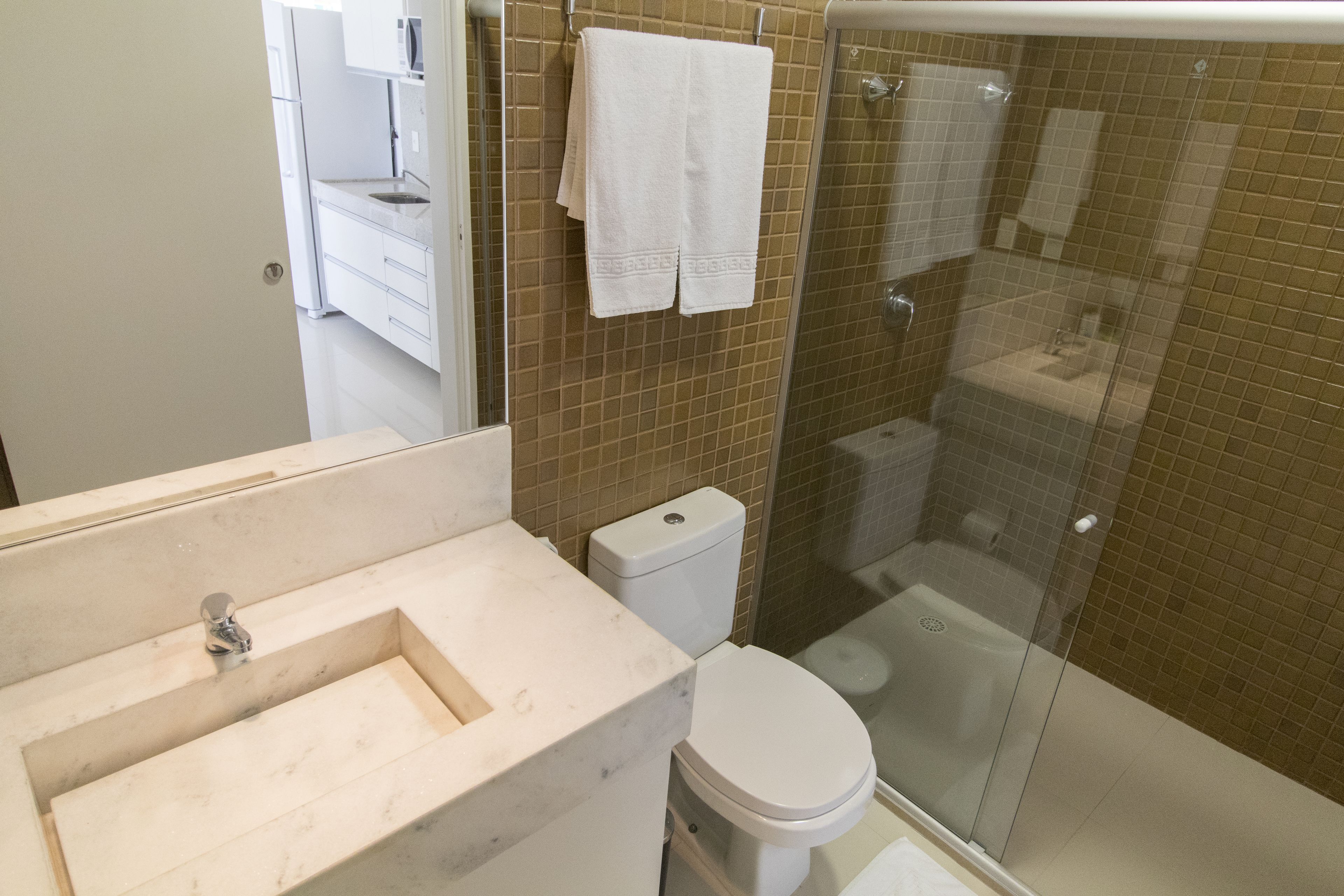 A bathroom with a marble sink, a toilet, and a glass-enclosed shower.
