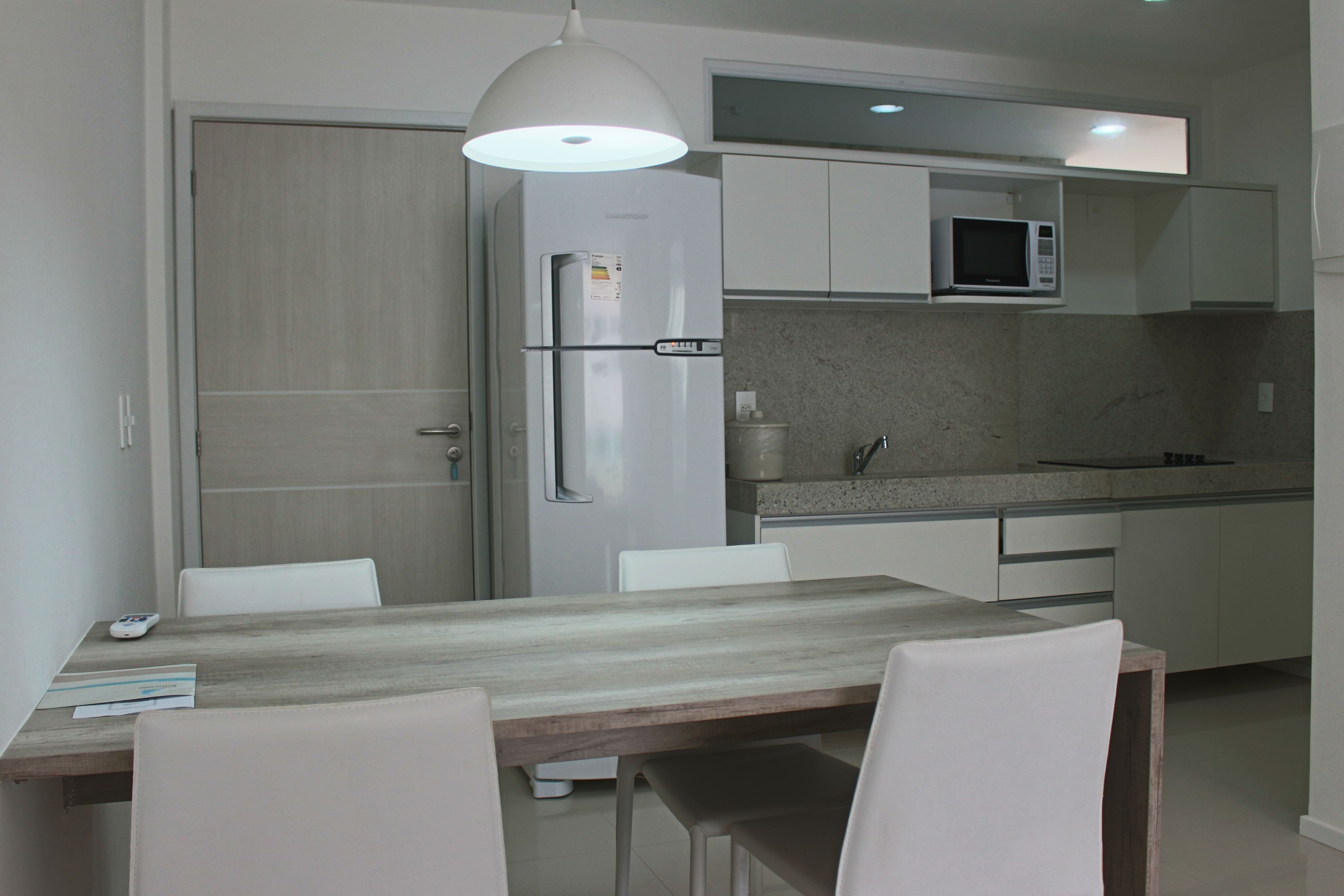 A modern kitchen with white cabinets, a built-in microwave, and a wooden dining table with chairs.
