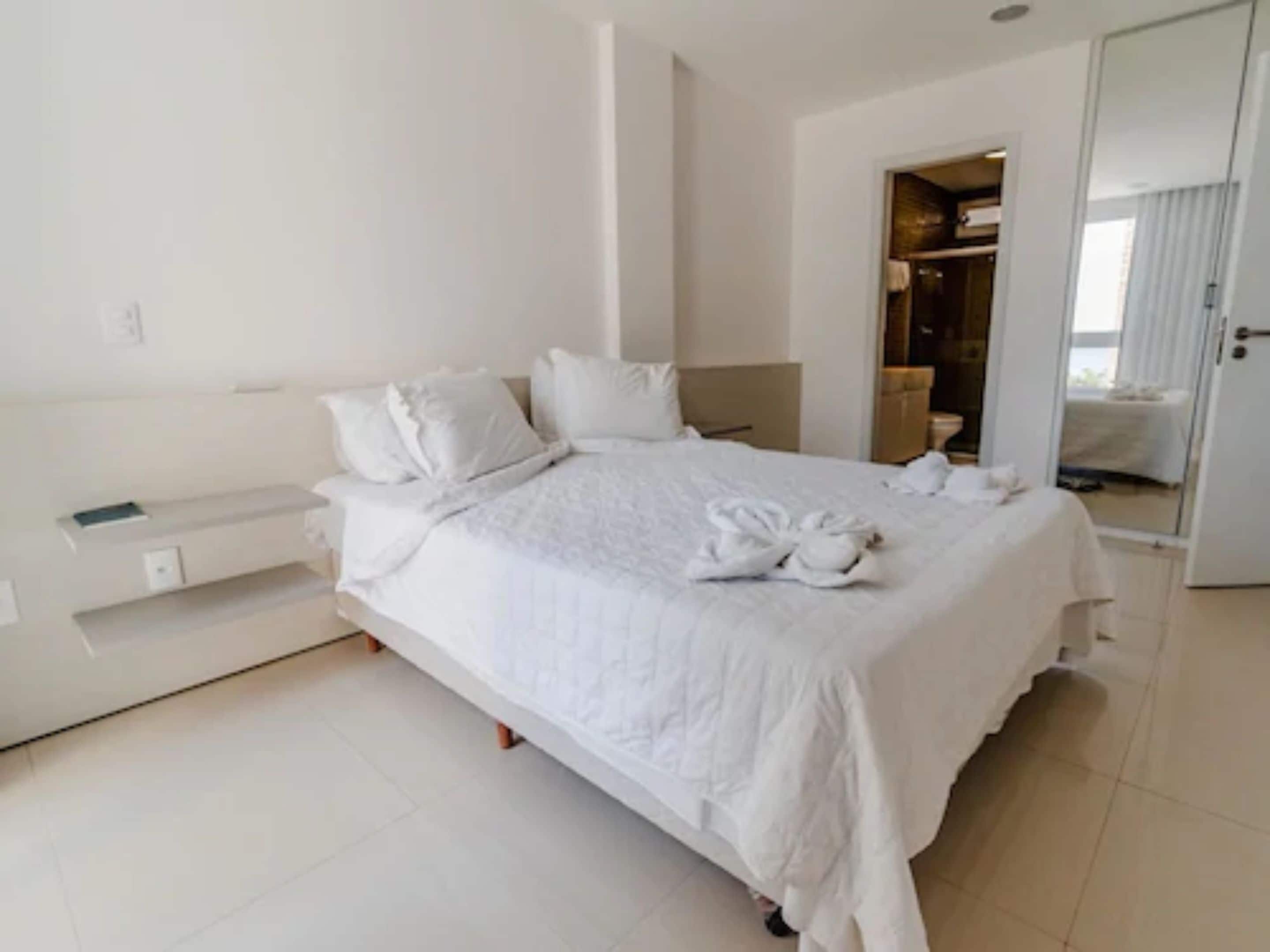 Una habitación de hotel moderna con una cama grande, una mesita de noche y un armario.