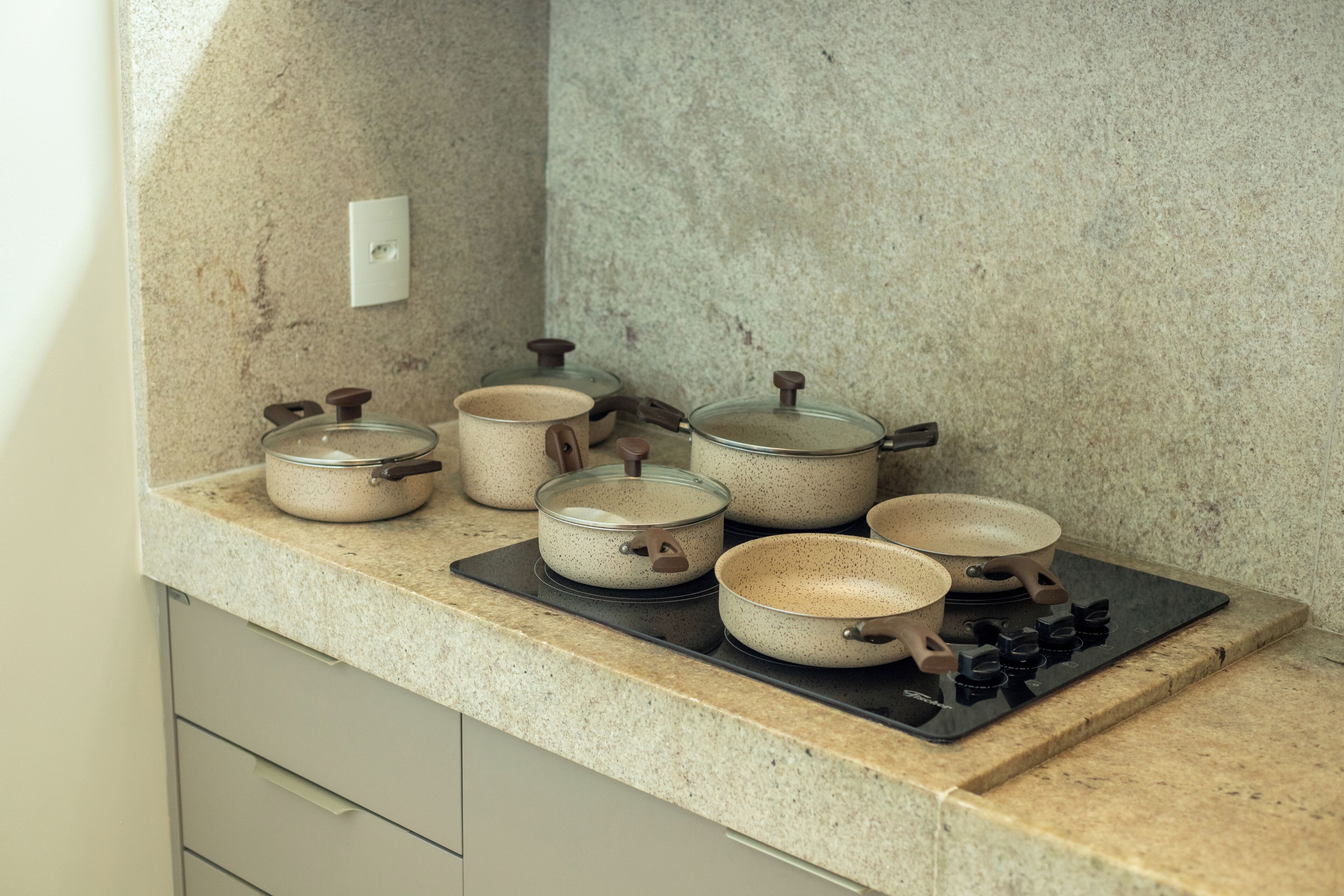 Una cucina con un piano di lavoro in granito, diverse pentole in ceramica e un fornello.