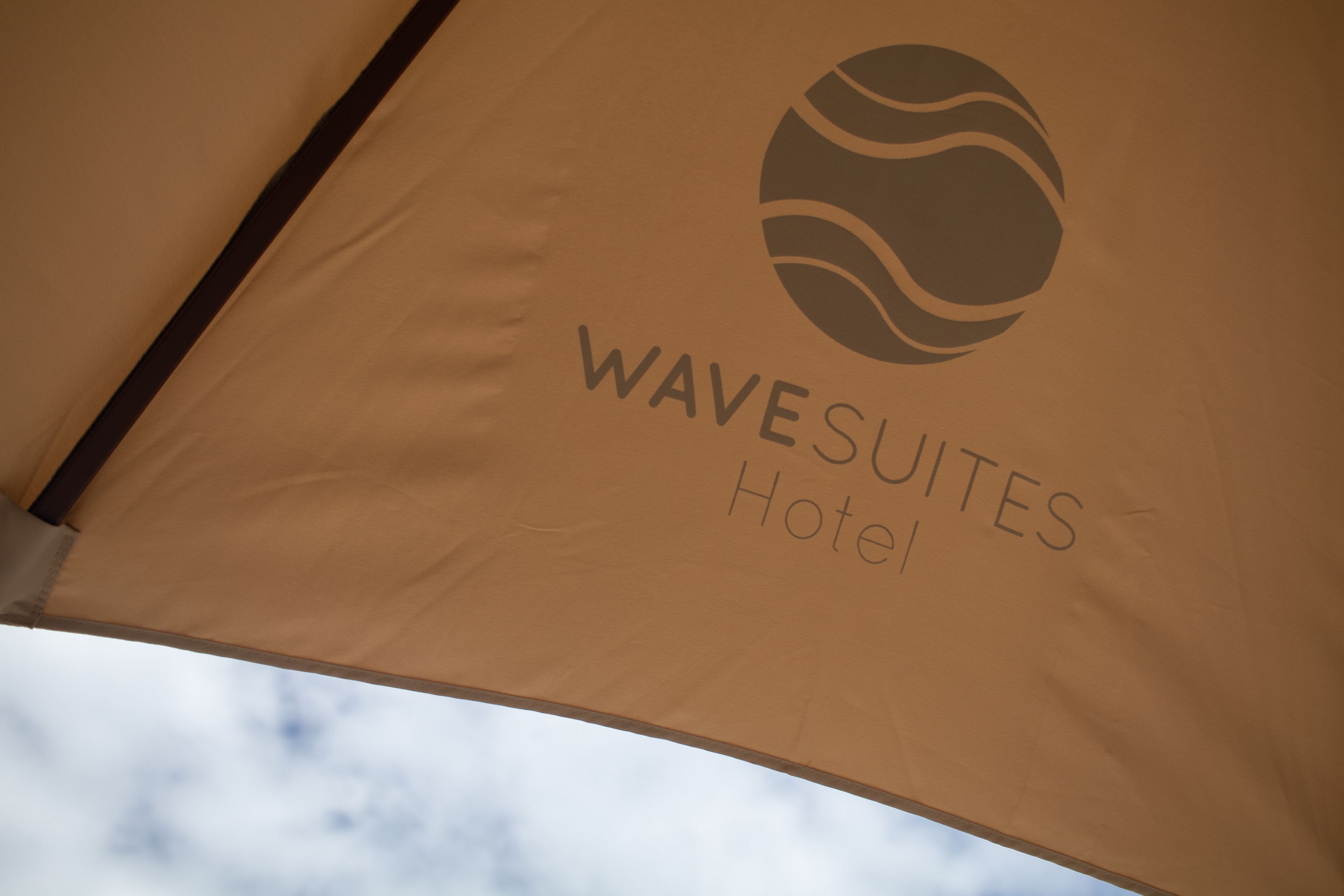 Uma tenda com o texto "WAVESUITES Hotel" e um logotipo estilizado de onda.