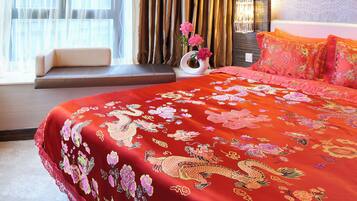 Quarto de hotel com uma cama grande, um banco junto à janela e um abajur decorativo.