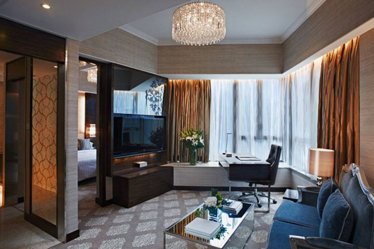 Een moderne hotelkamer met een grote televisie, een bank, een bijzettafeltje en een bureau met een stoel.