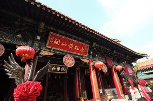 Un edificio tradicional chino con decoraciones elaboradas, incluyendo faroles rojos y estatuas doradas.