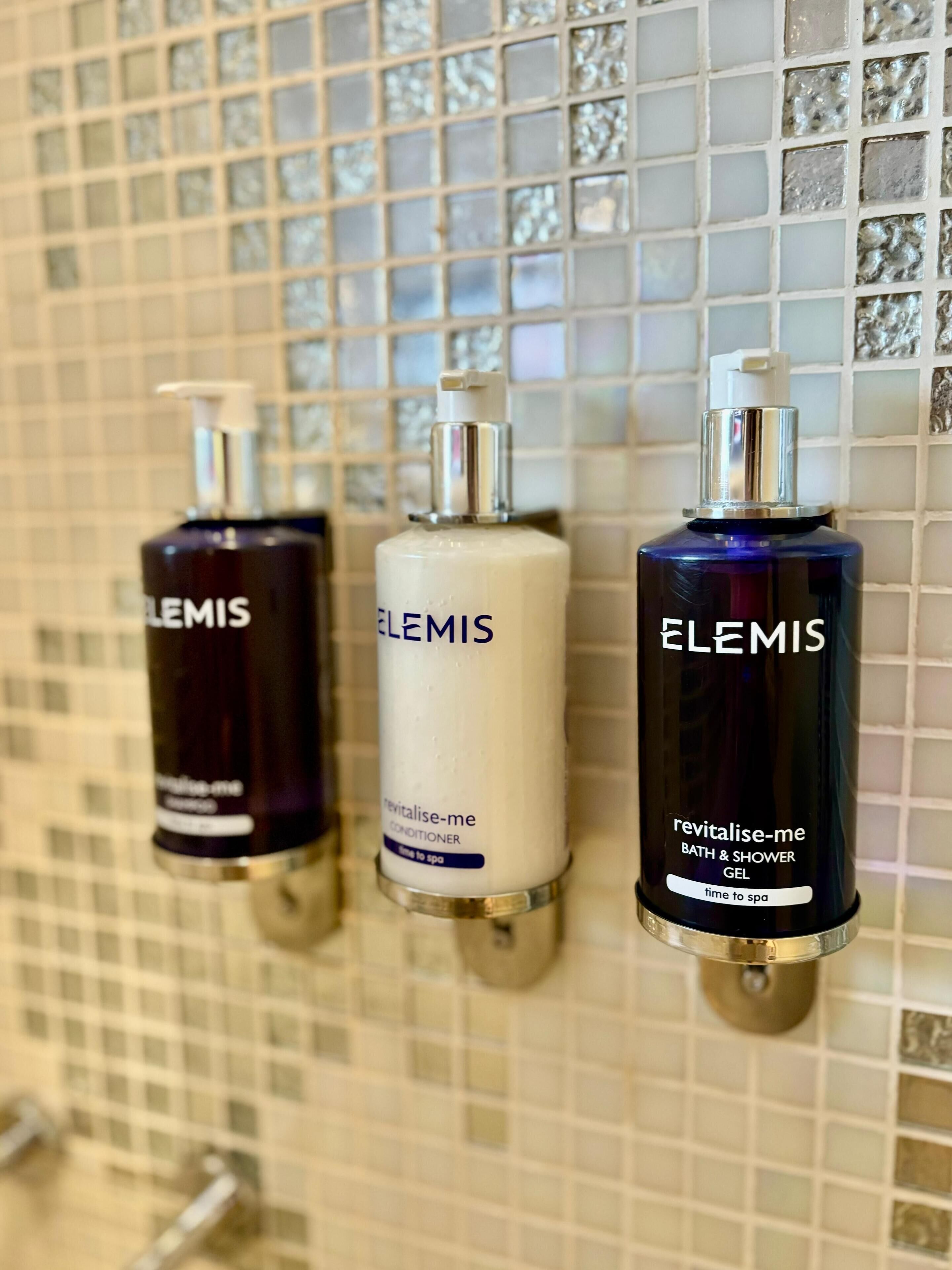 Drei Elemis Badedarstellungen an einer gefliesten Wand.