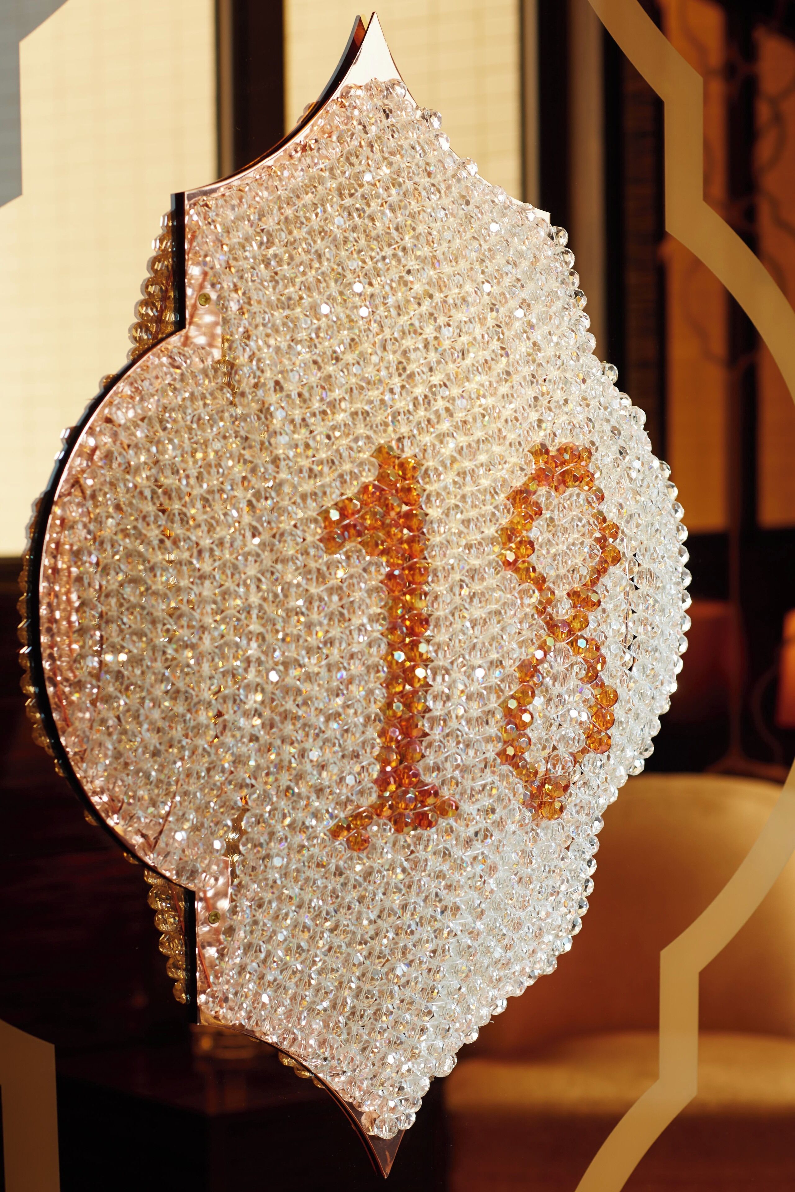 A decorative item with a number 18, possibly a plaque or sign, adorned with numerous small, reflective elements.
