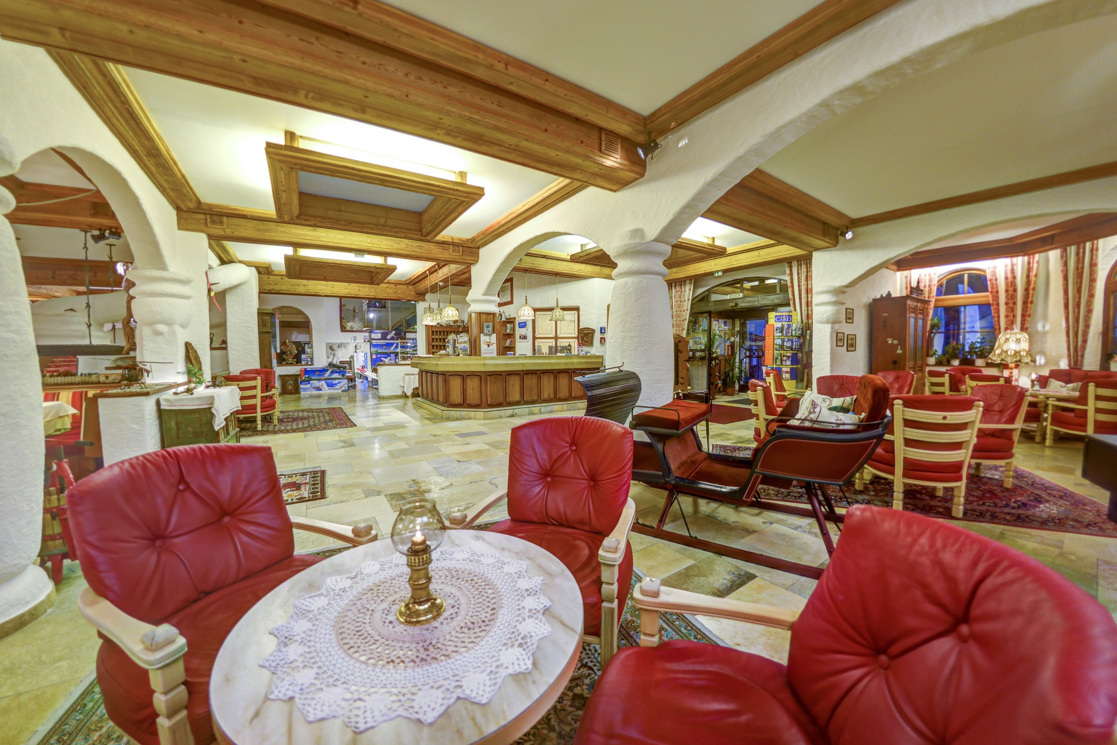 A spacious lobby with red leather chairs, a central bar area, and wooden beams on the ceiling.