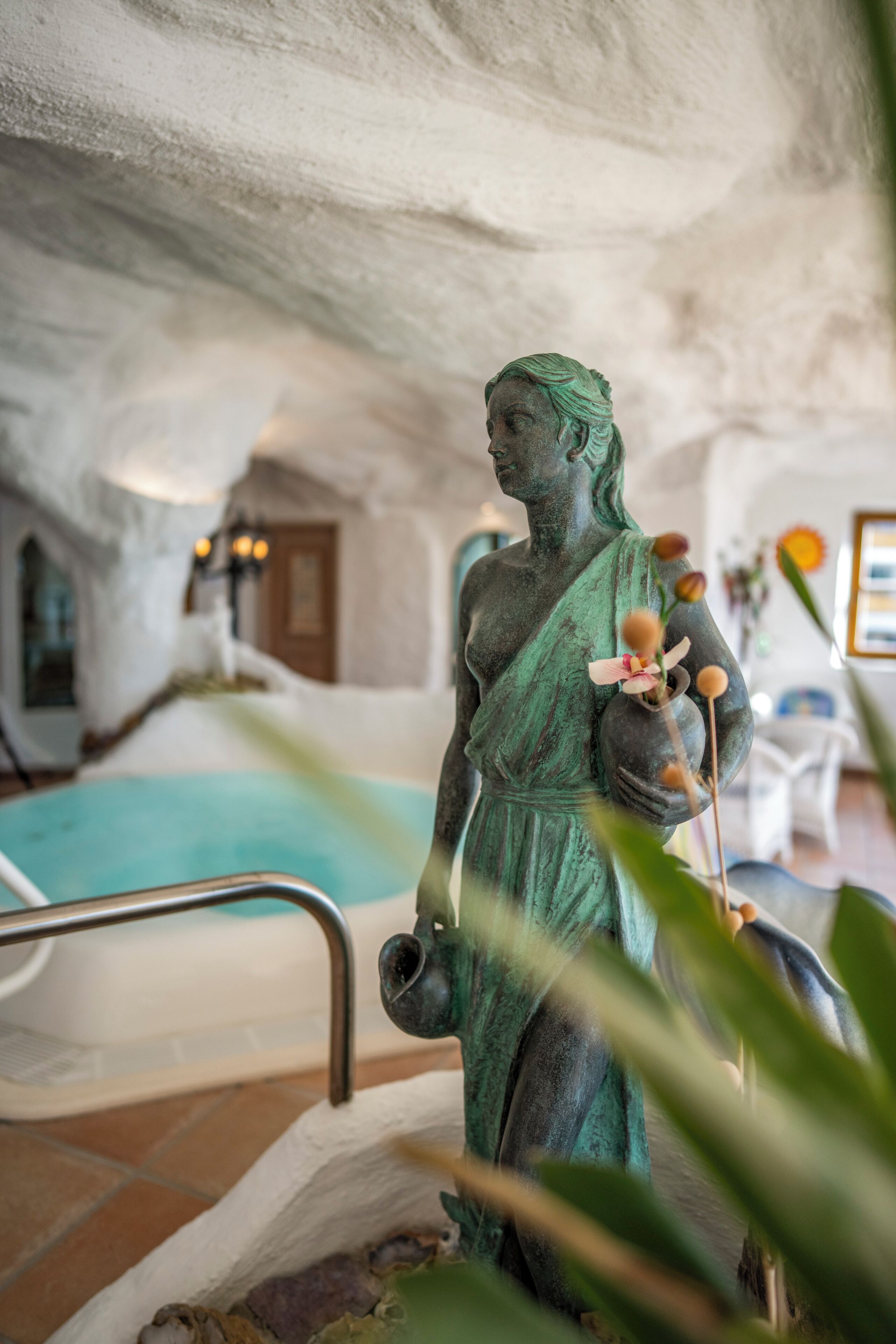 Una estatua en una habitación con piscina, una puerta y una silla.