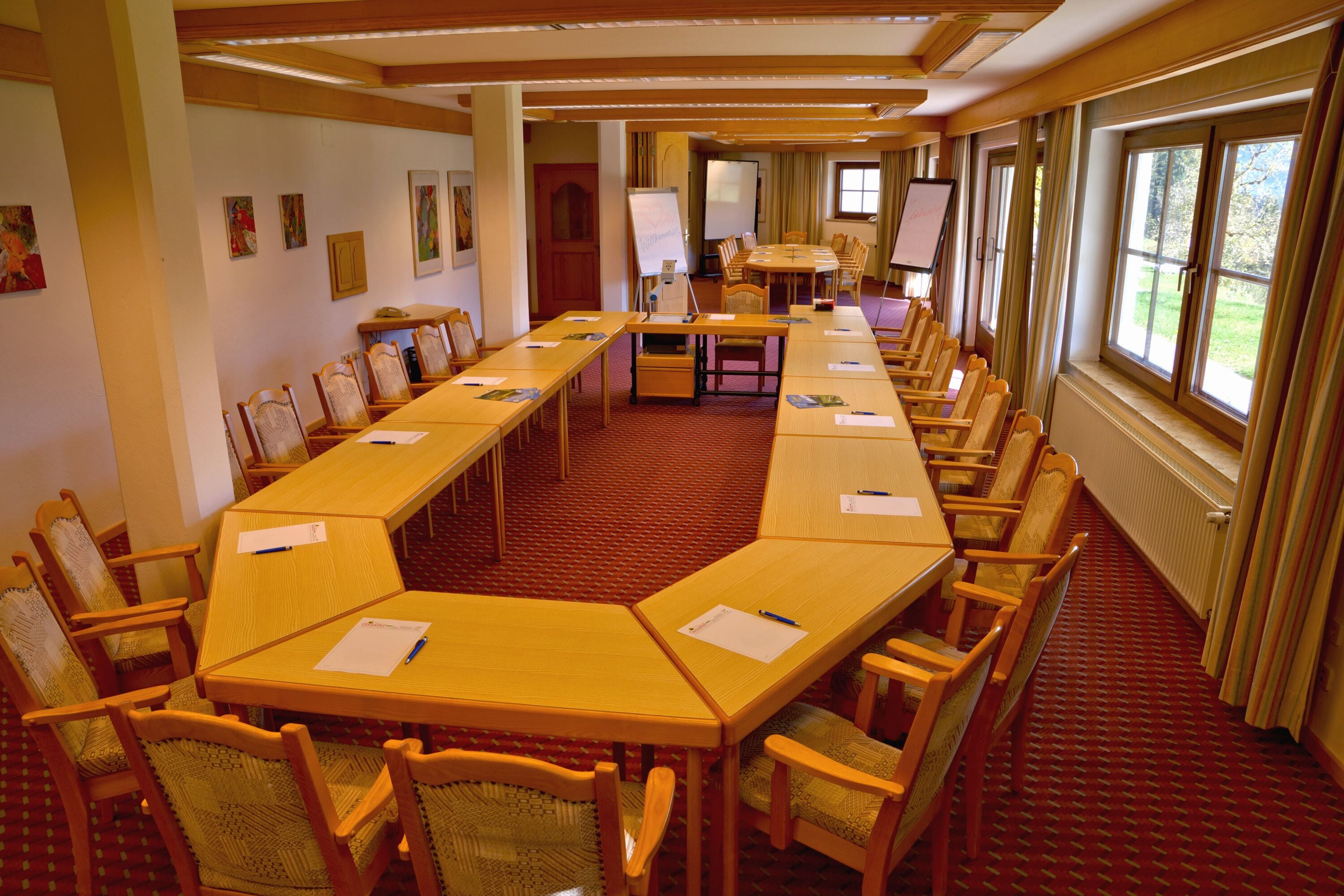 Una sala conferenze con un lungo tavolo, sedie, una lavagna e uno schermo per proiettore.