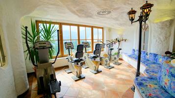 A room with exercise equipment, a large window, and a sofa with a colorful design.