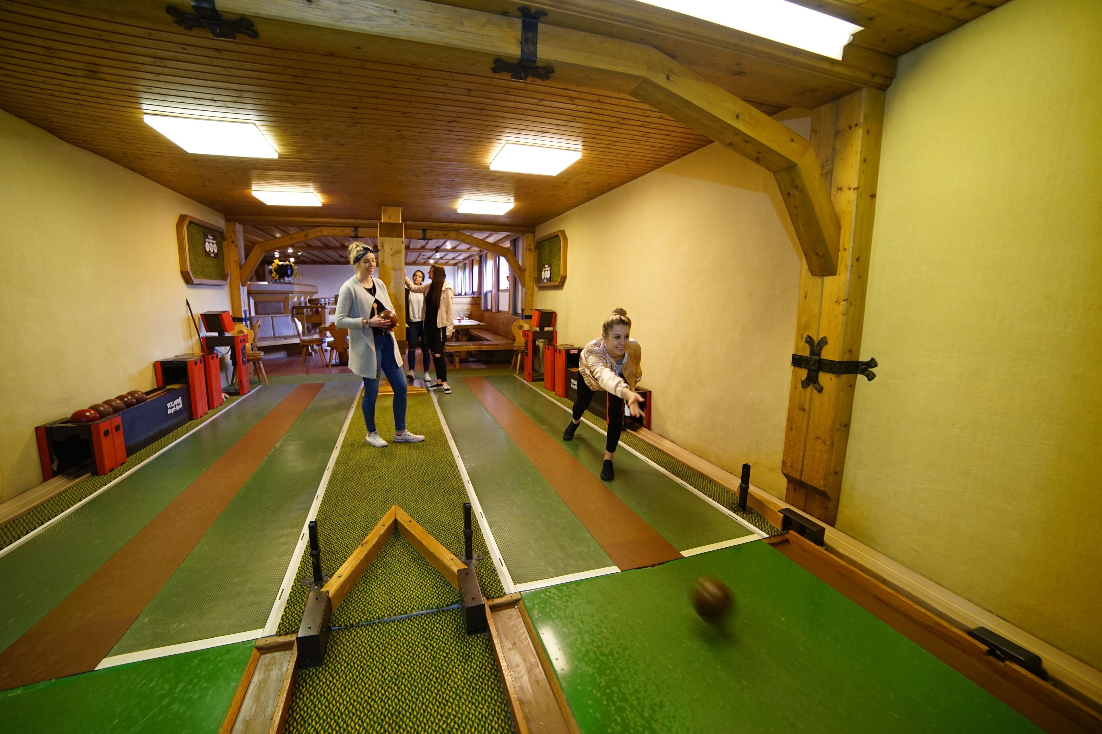 An indoor sports facility with a green floor, wooden beams, and a target for shooting practice.