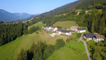 Un complejo turístico de montaña con varias edificaciones de estilo chalet, una piscina e iglesia.