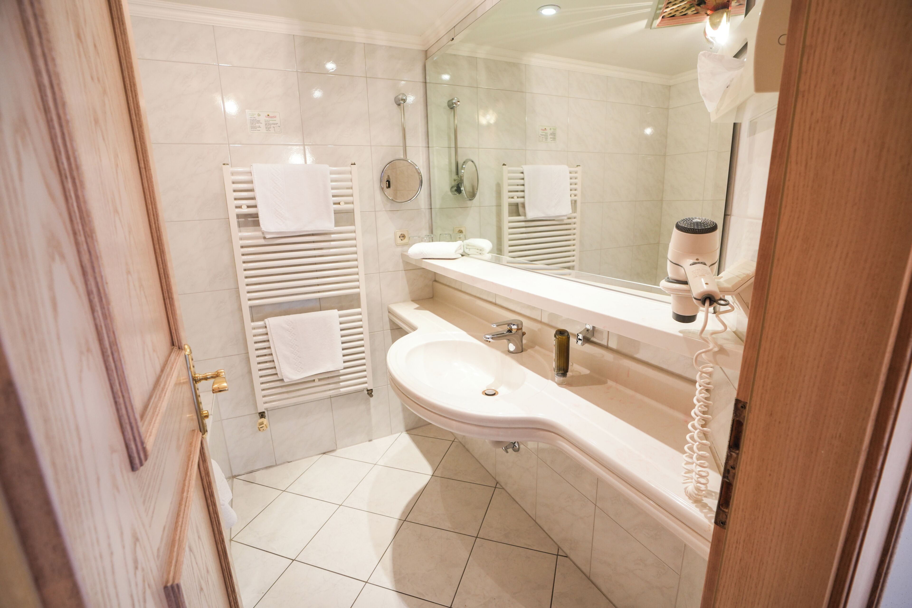 A modern bathroom with a sink, mirror, towel racks, and a shower.