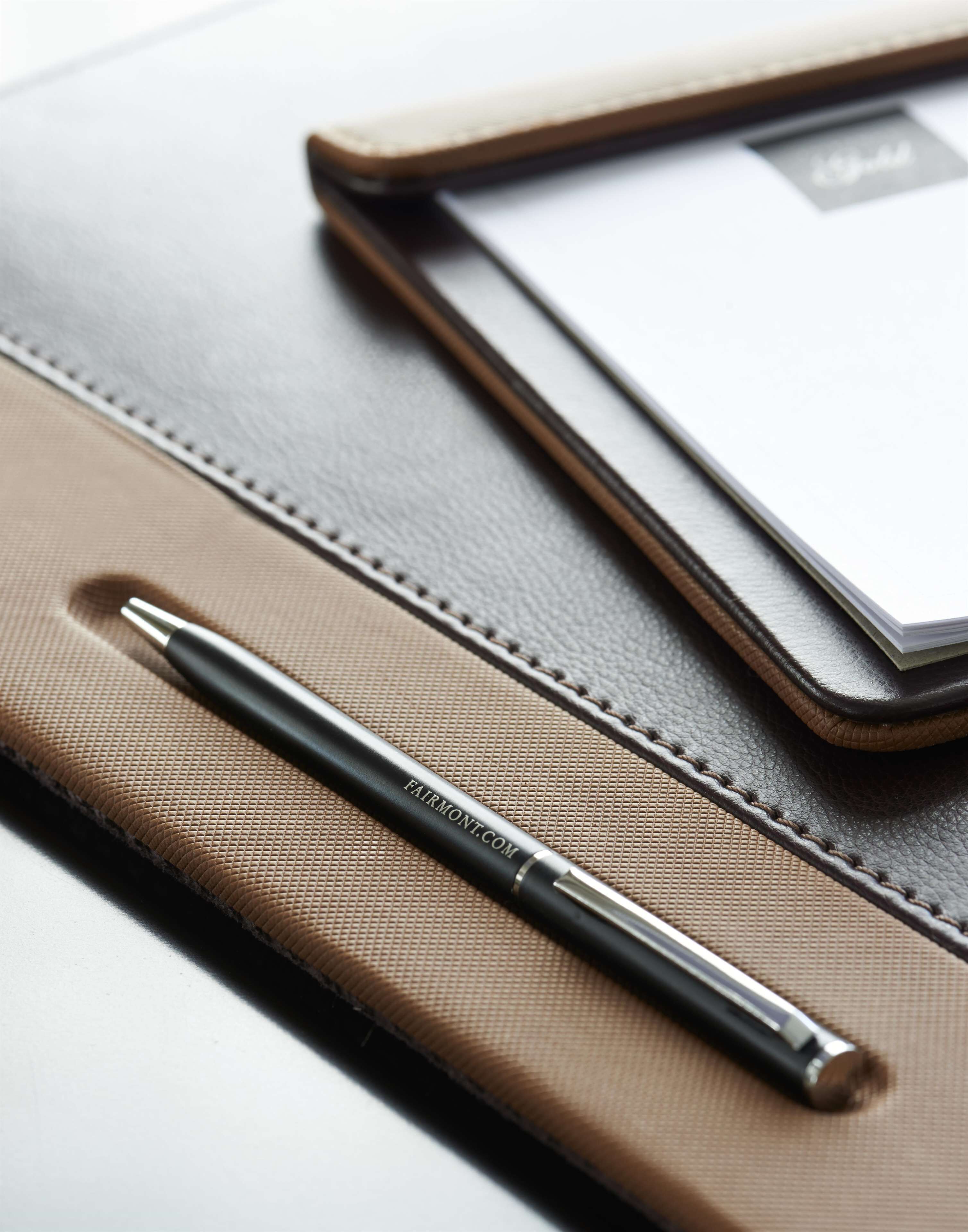 A leather-bound notebook with a pen on top, placed on a white surface.