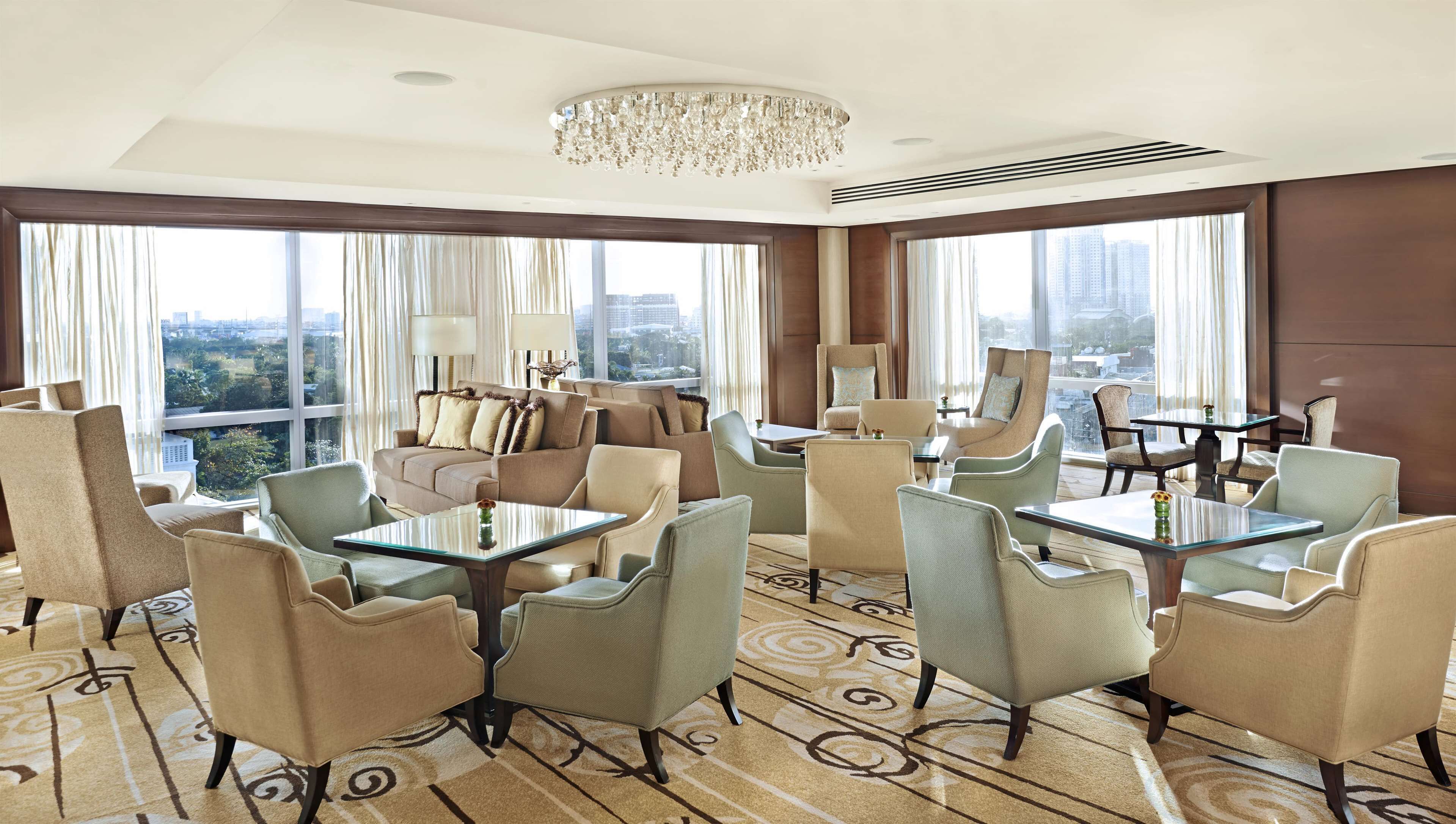 A spacious hotel lobby with a modern chandelier, comfortable seating, and large windows offering city views.