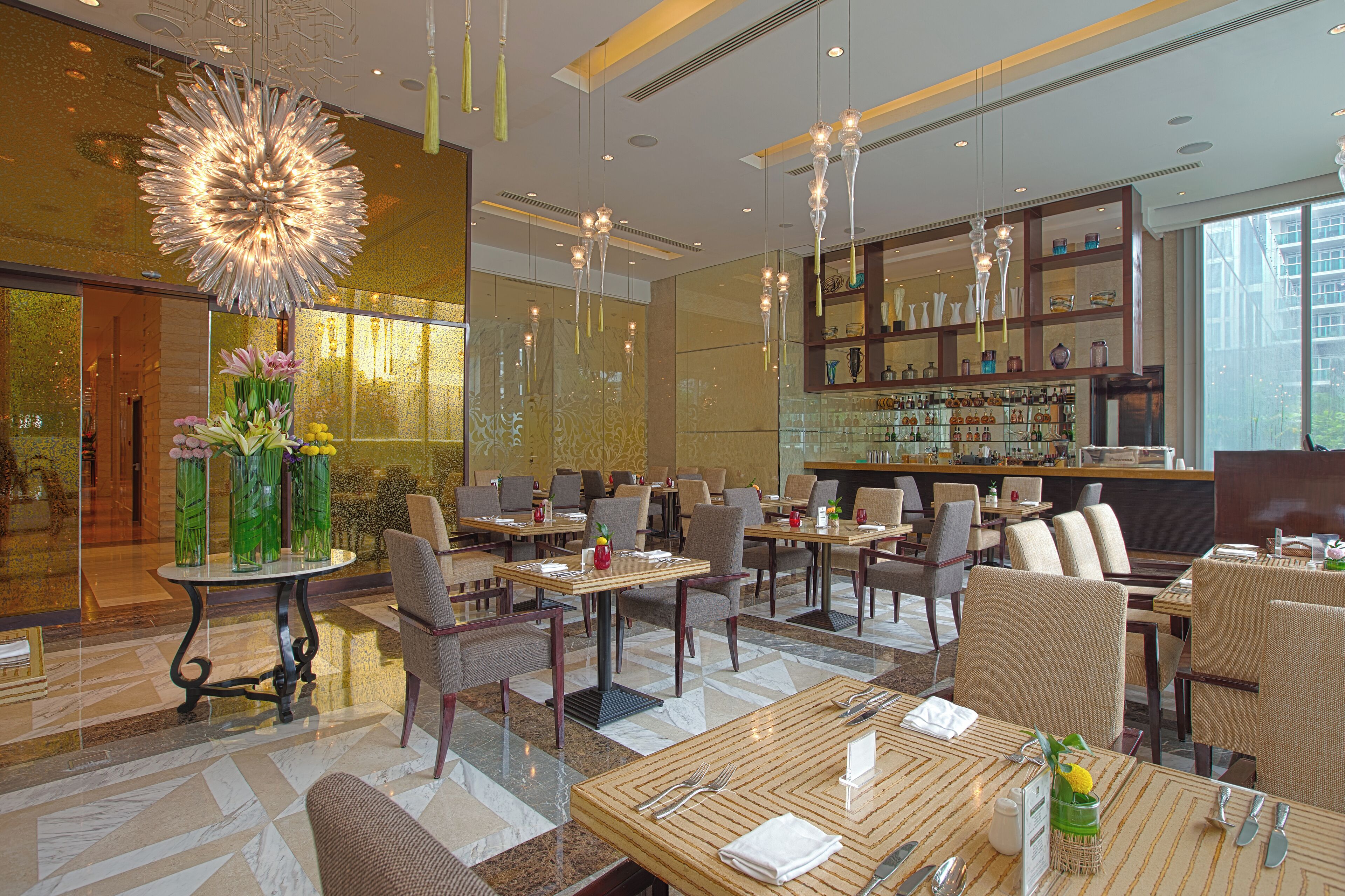 A modern restaurant with multiple dining tables, chairs, and a bar area.
