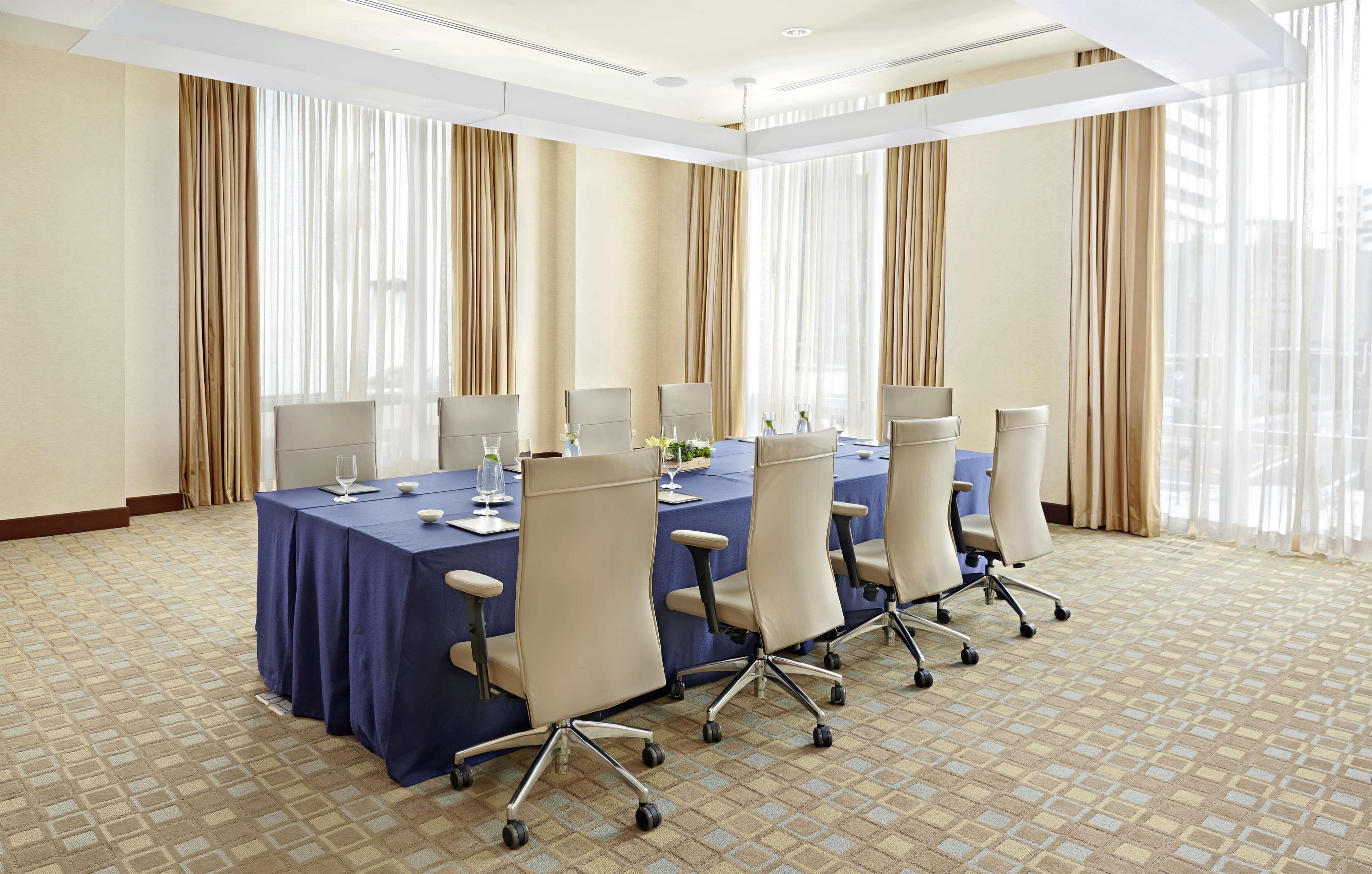A conference room with a long table, chairs, and a carpeted floor.