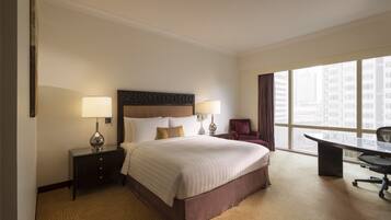 A hotel room with a large bed, two bedside tables with lamps, a desk, and a chair.