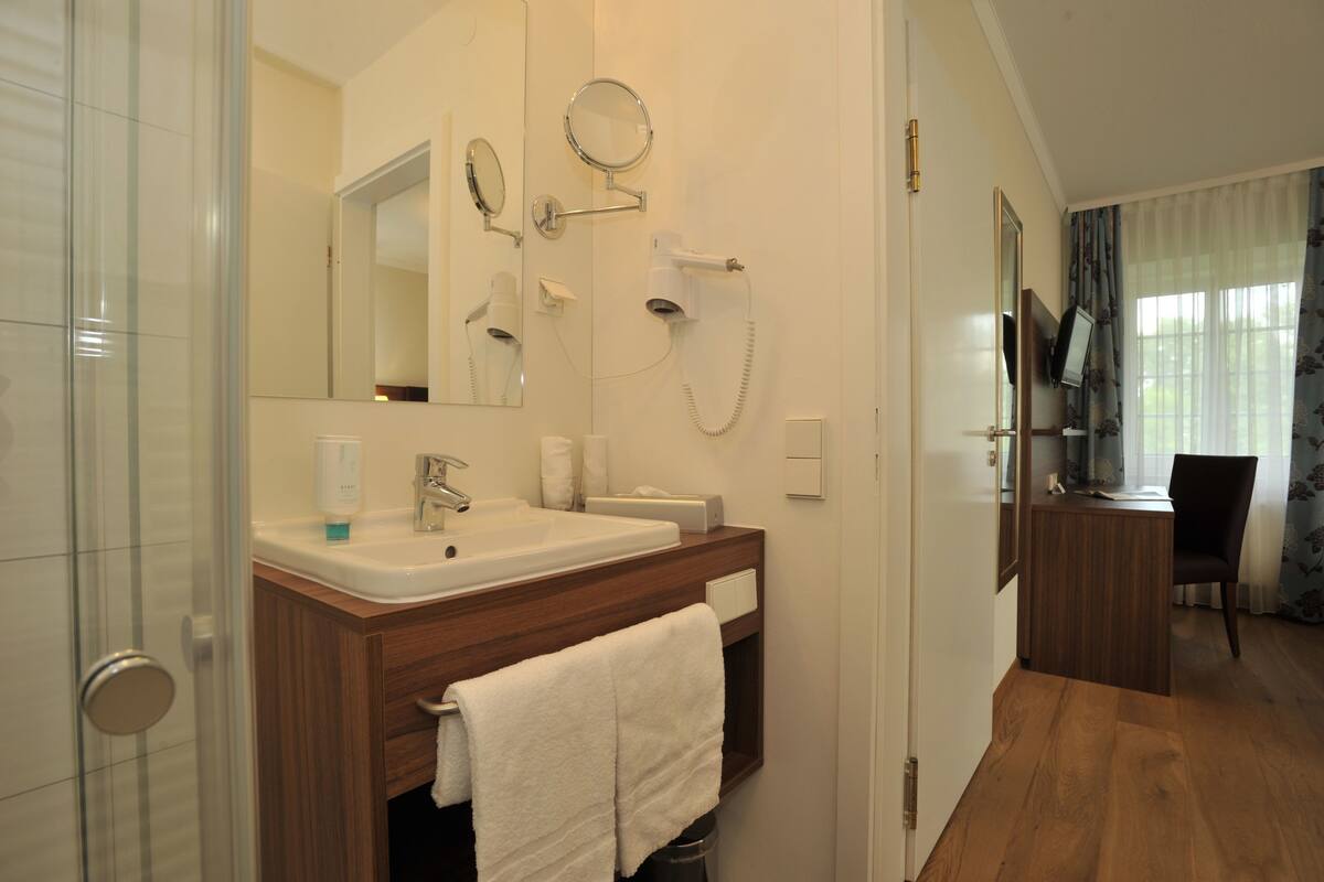 Une salle de bain moderne avec une douche à parois de verre, un meuble-lavabo avec un miroir et un placard en bois.
