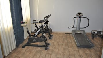 A home gym with a stationary bike, a treadmill, and a rowing machine.