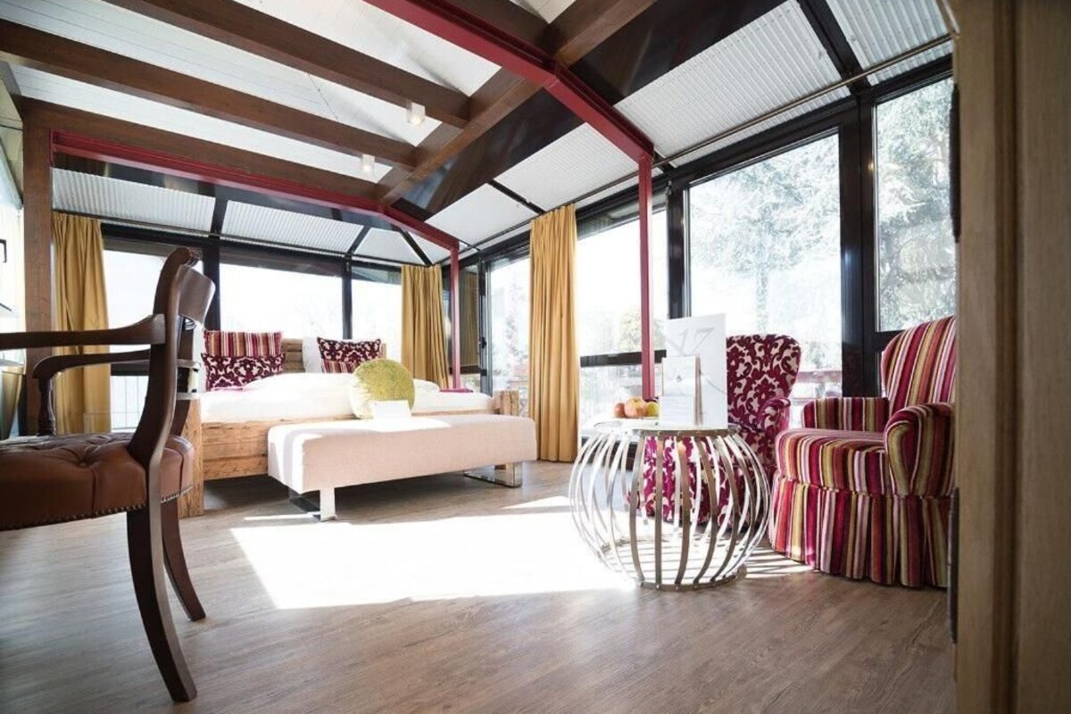 A spacious room with a bed, a round table, and striped chairs.