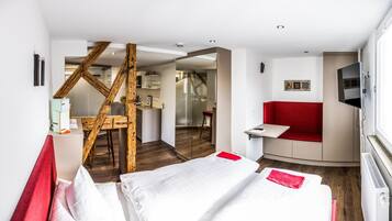 Ein Hotelzimmer mit einem Bett, einer roten Couch, einem Fernseher und einer Holzkonstruktion.