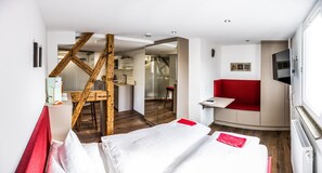 A hotel room with a bed, a red couch, a TV, and a wooden structure. - Hotel Restaurant Krehl S Linde (Stuttgart)