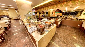 A buffet setup with various food stations and a seating area. - Hotel Taiamã (CUIABA)