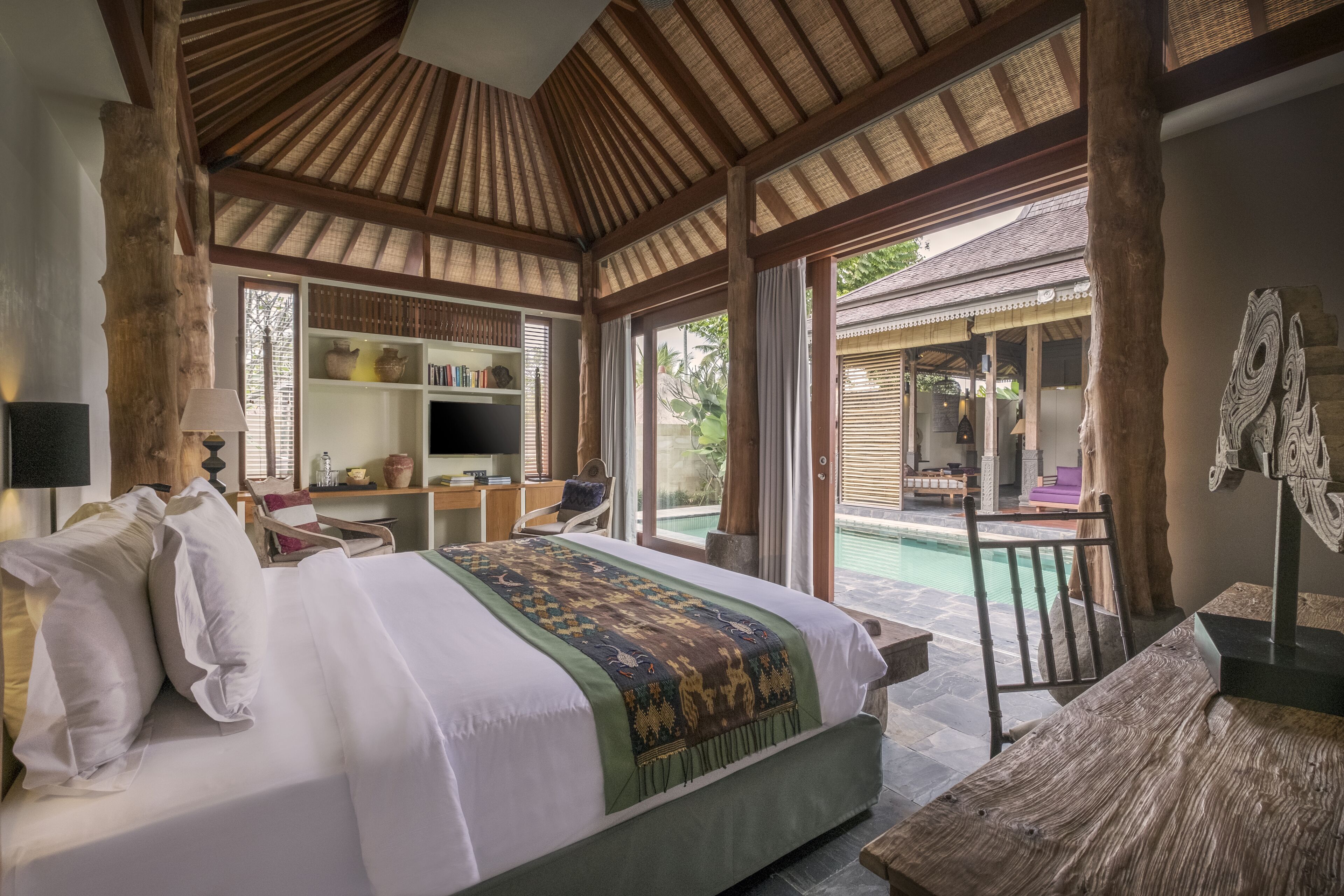 Un dormitorio amplio con una cama grande, un escritorio y vistas a la zona de la piscina al aire libre.