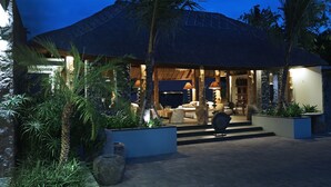 A resort with a thatched-roof structure, outdoor seating area, and tropical plants. - The Purist Villas & Spa (Ubud)