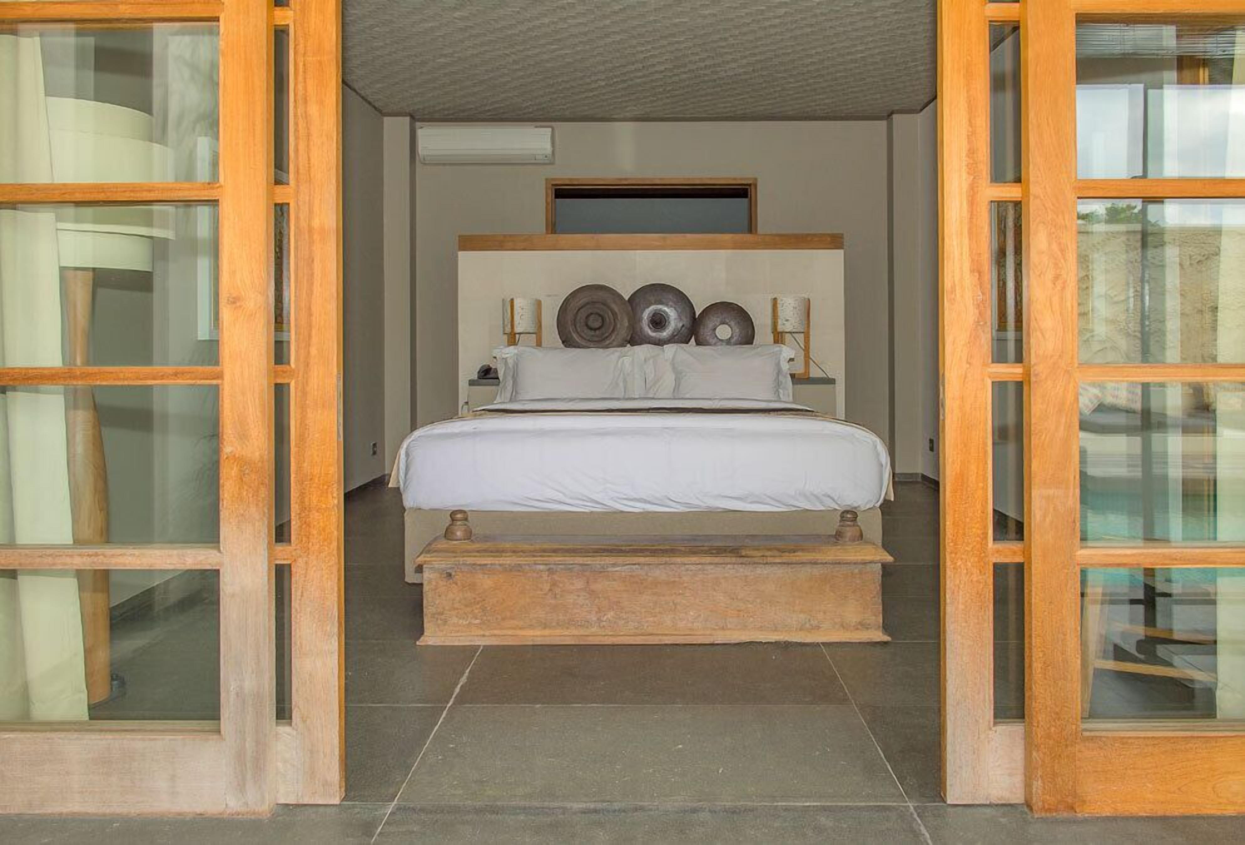 Quarto com estrutura de cama em madeira, cabeceira com pratos decorativos e janela com vista para o exterior.