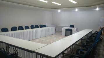 Una sala de conferències amb una taula llarga, cadires, un projecte i una pissarra.